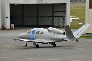 Ein kleines Flugzeug steht vor einer Flugzeughalle