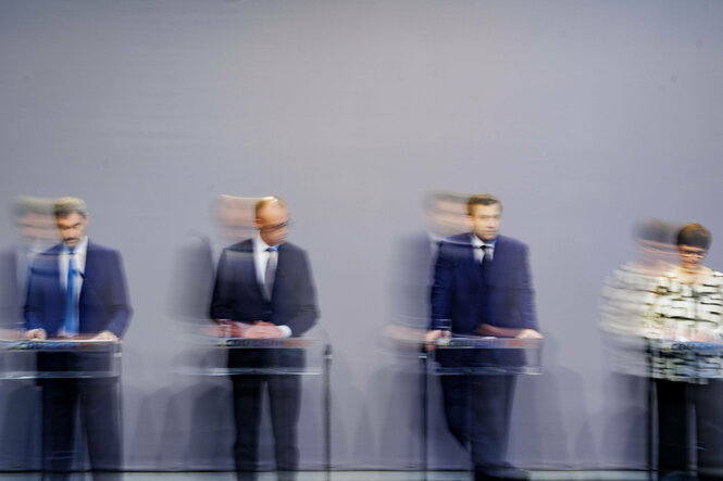 Markus Söder, Friedrich Merz, Lars Klingbeil und Saskia Esken stehen nebeneinander hinter Rednerpulten, das Bild ist verschwommen