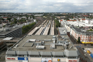 Ein graues Gebäude vor mehreren überdachten Bahngleisen.